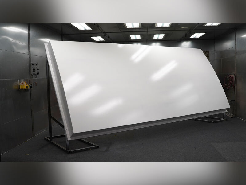Large, ground-based radome in paint booth with white, reflective paint on its surface